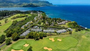 Vue aérienne d’un terrain de golf, avec des immeubles résidentiels, une végétation luxuriante et une côte.