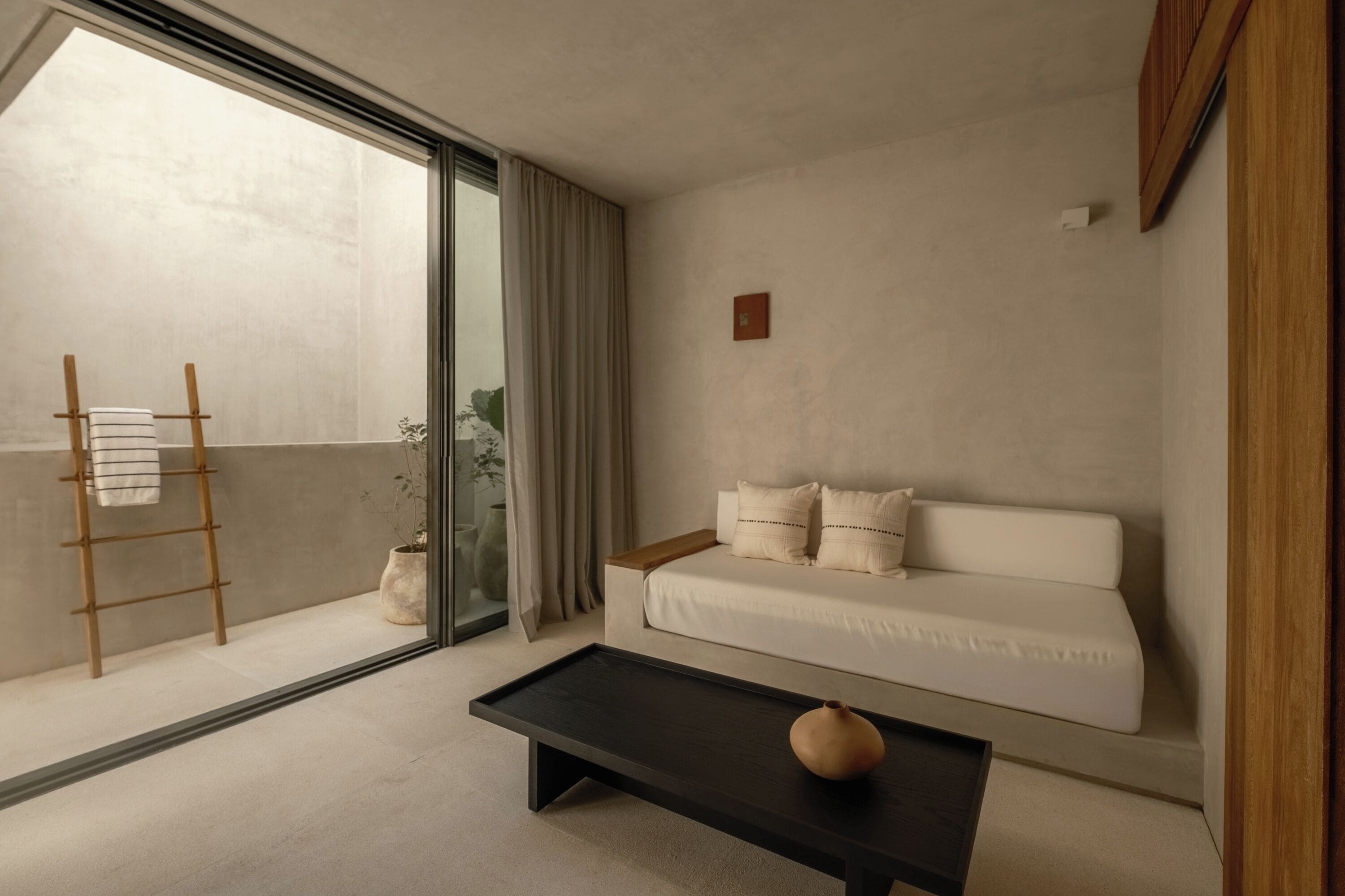 A modern living room with a sofa, a coffee table, a ladder, and a potted plant.