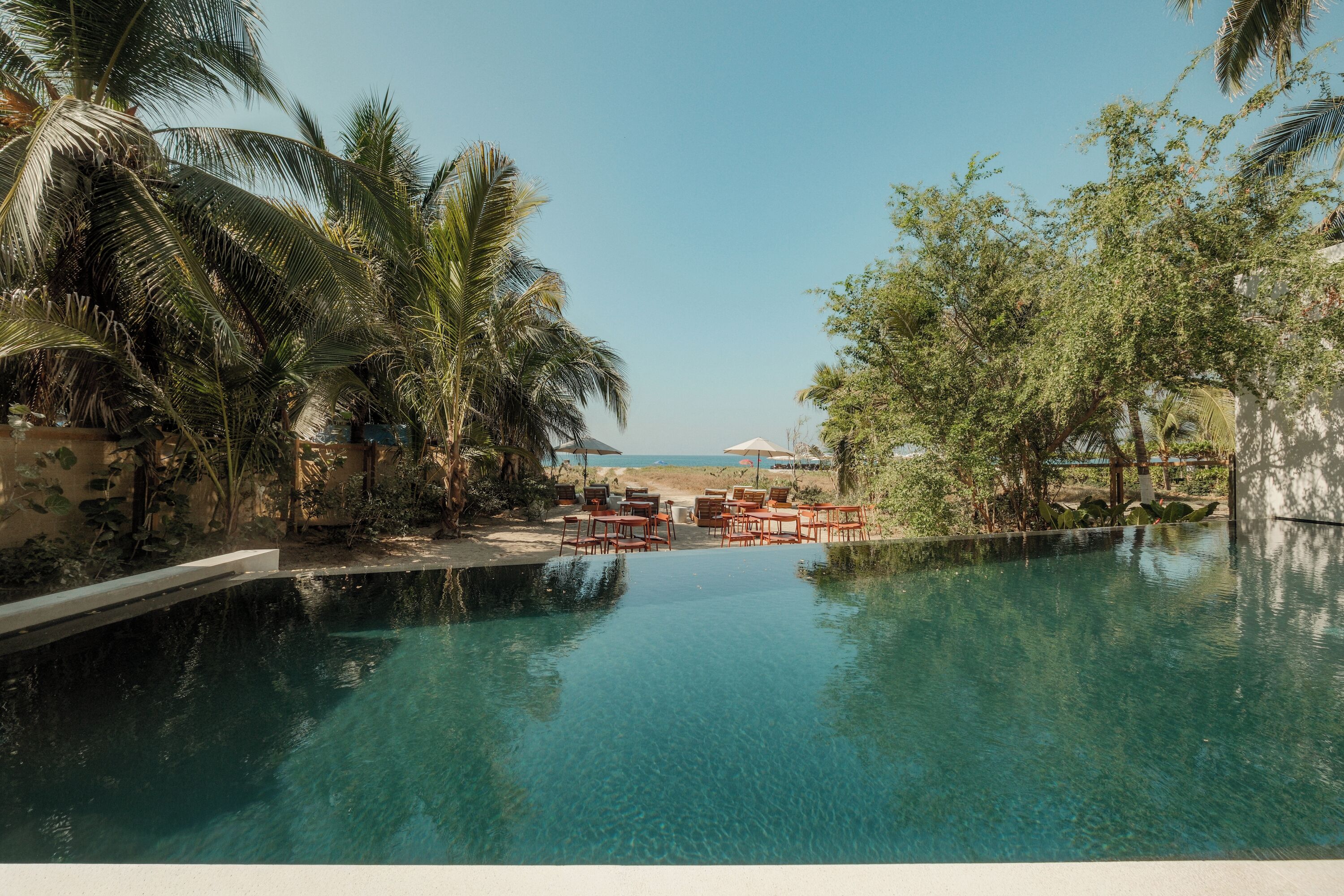 Una piscina al aire libre, sombrillas, sillones reclinables de piscina