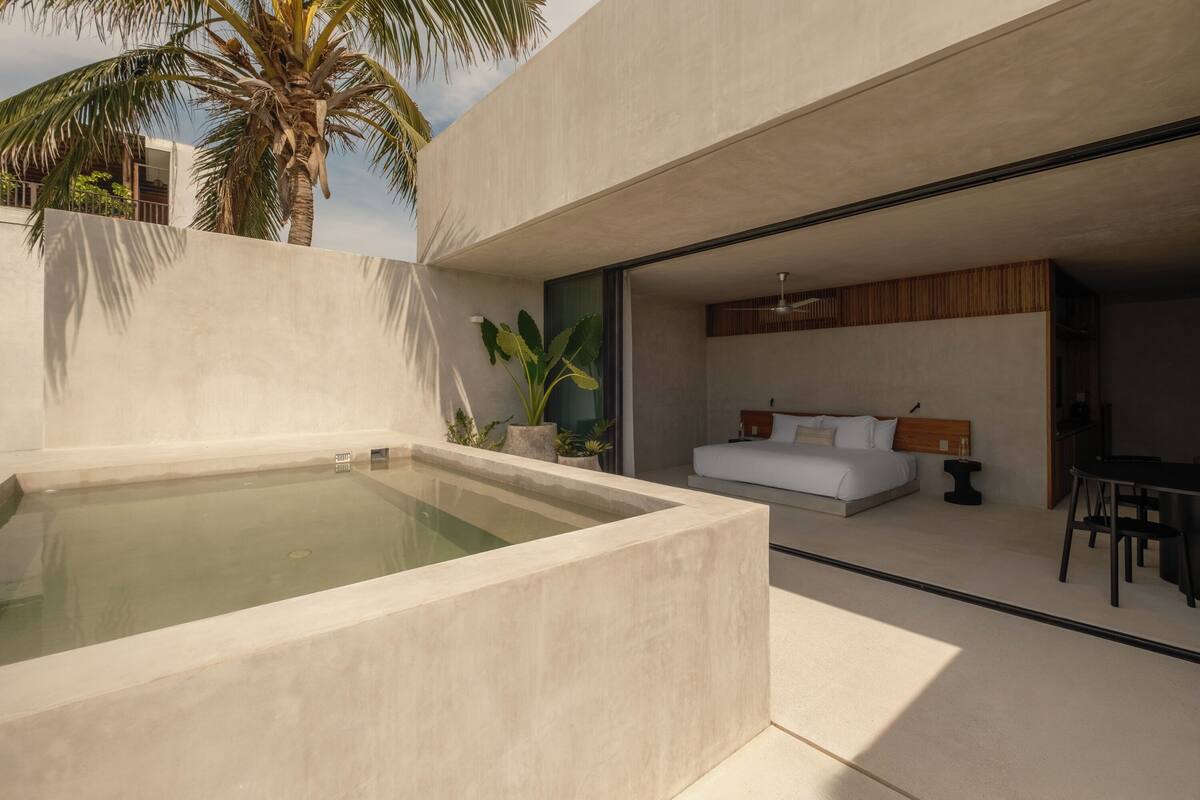 A modern bedroom with a large bed, a small table, and a seating area.