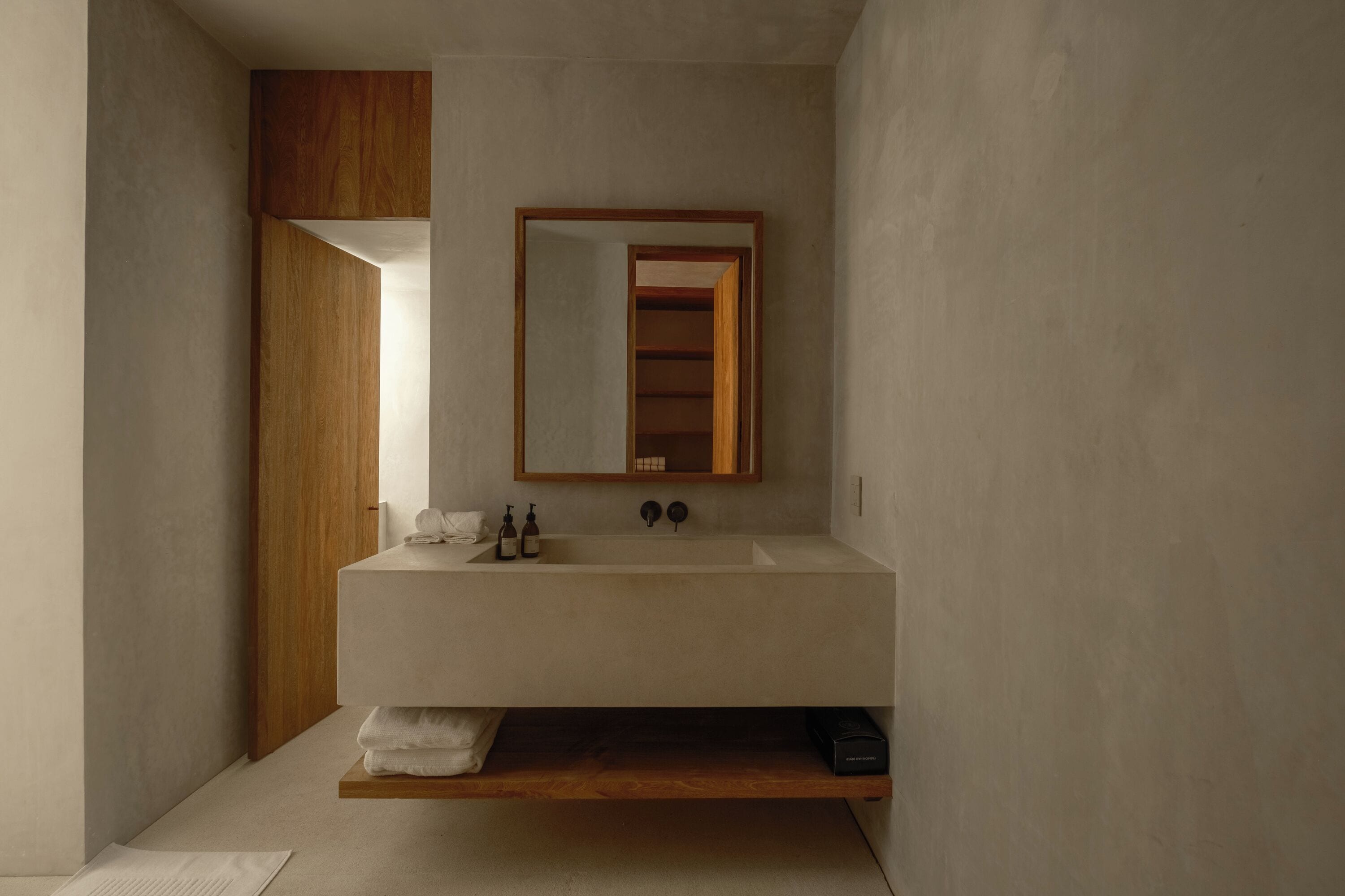 Un baño moderno con un lavamanos grande, estanterías de madera y un espejo.