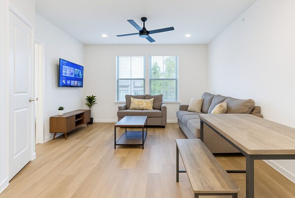 Ein modernes Wohnzimmer mit Sofa, Couchtisch und Fernseher.