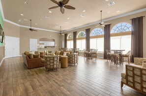 Un espacio habitable amplio con techo alto, varios ventiladores de techo y ventanas grandes con cortinas.