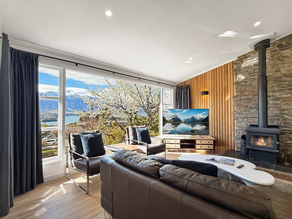 A modern living room with a large window, a fireplace, and a sofa.