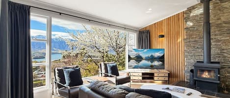 A modern living room with a large window, a fireplace, and a sofa.