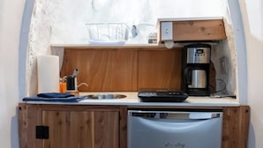 A compact kitchenette with a coffee maker, a dish rack, and a dish soap dispenser.