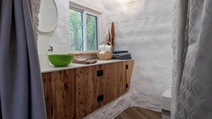 A bathroom with a wooden vanity, a green bowl, a basket, and a window.