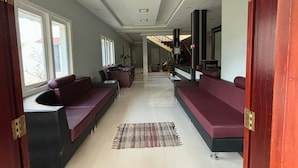 A spacious living room with a high ceiling, built-in seating, and a staircase leading to an upper level. - KODAI FOGGY (Kodaikanal)