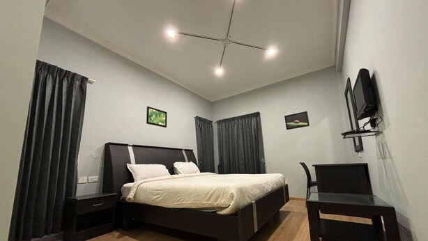 A bedroom with a bed, two nightstands, a chair, a TV, and a ceiling fan. - KODAI FOGGY (Kodaikanal)