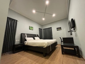 A bedroom with a bed, two nightstands, a chair, a TV, and a ceiling fan. - KODAI FOGGY (Kodaikanal)
