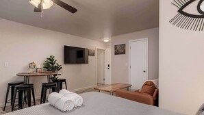 A hotel room with a bed, a desk, a chair, a television, and a door. - Downtown Art Deco - Studio (Anchorage)