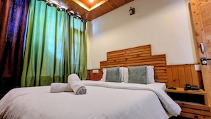 A neatly made bed with white linens and two pillows, a wooden headboard, and a green curtain.