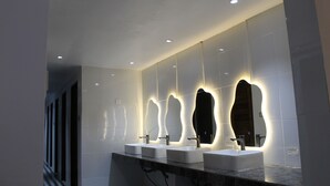 Une salle de bain moderne avec trois lavabos et un grand miroir.