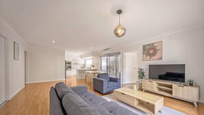 A modern living room with a large grey sectional sofa, a coffee table, and a TV stand.