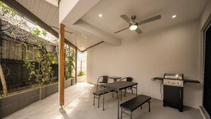 A patio with a table and chairs, a ceiling fan, and a barbecue grill.