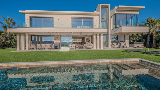Ein modernes, zweistöckiges Haus mit einem großen Schwimmbecken davor.