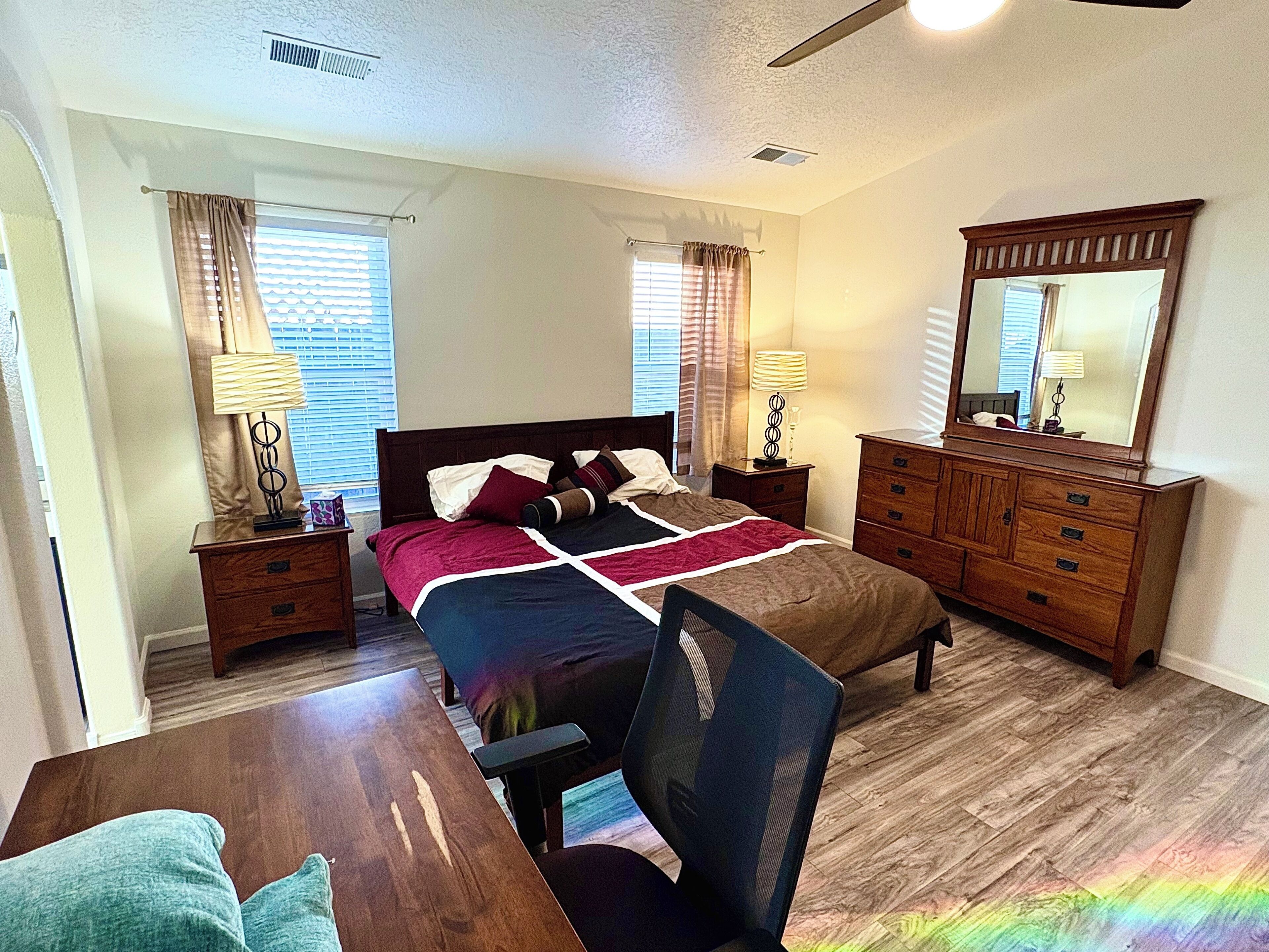 Un dormitorio con cama, escritorio, silla, cómoda y espejo.