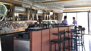 Un'area bar con un design moderno del soffitto, sgabelli da bar e un bancone bar ben fornito.