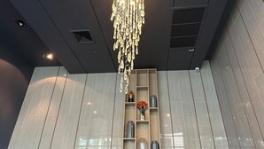 Un interno moderno con un lampadario decorativo, illuminazione a incasso e un'unità contenitore con oggetti decorativi.