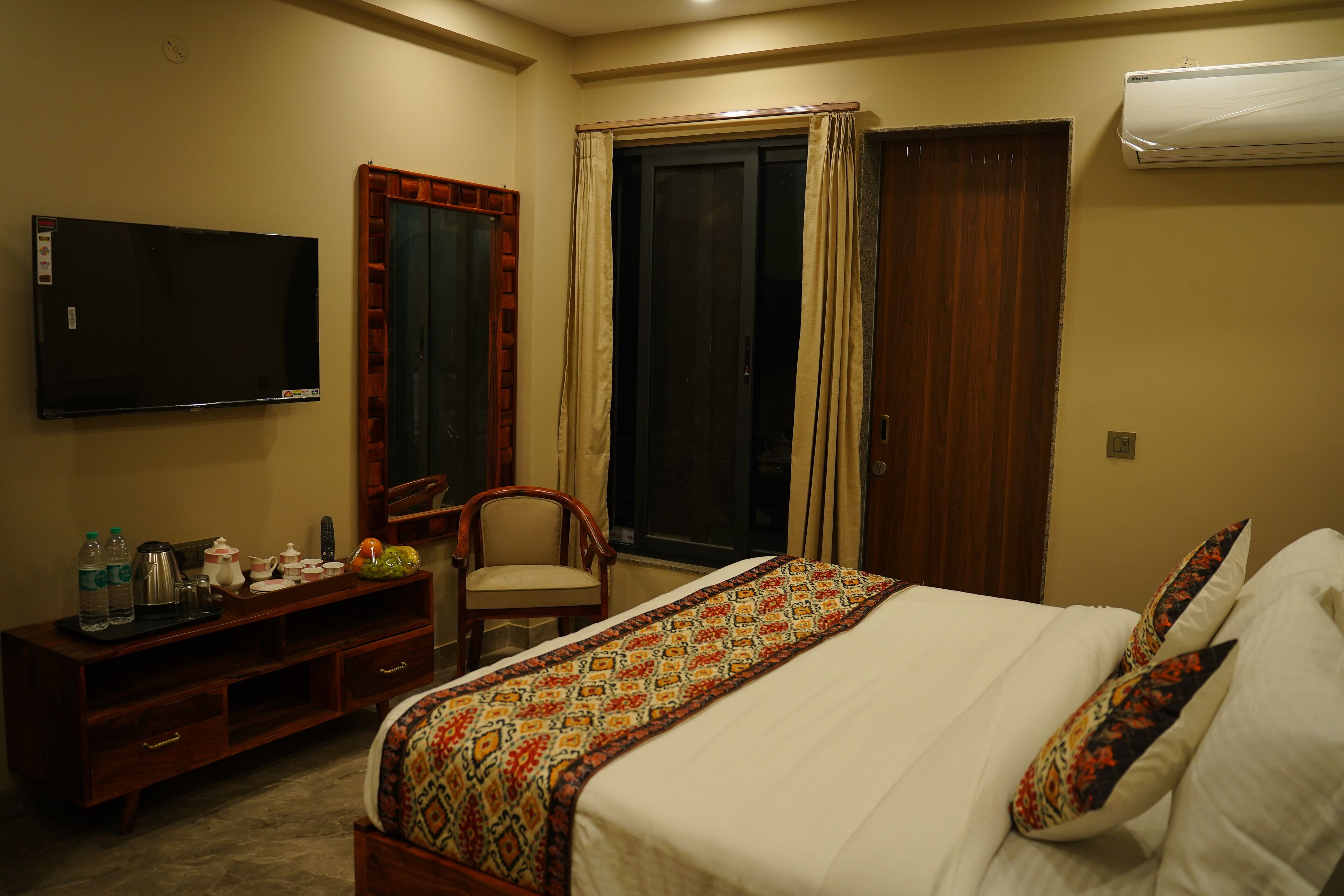 A hotel room with a bed, a TV, a desk with a chair, and a wardrobe.