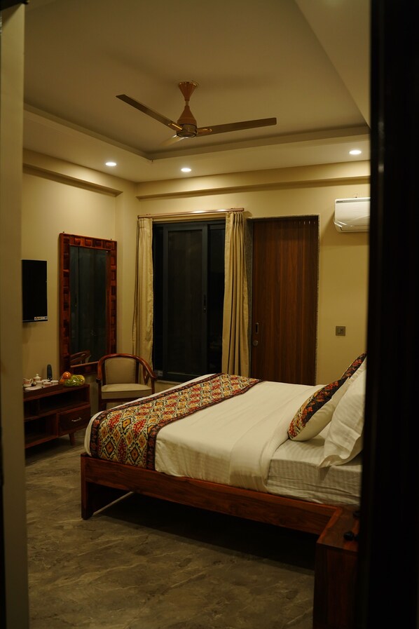 A bedroom with a bed, a ceiling fan, a wardrobe, a mirror, and a desk with a chair.