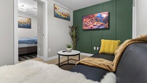 A modern living room with a sofa, a small round table with a plant, and artwork on the walls. - Guest Suite in Edmonton(King bed & Driveway parking),Separate Entrance & Heating (Edmonton)