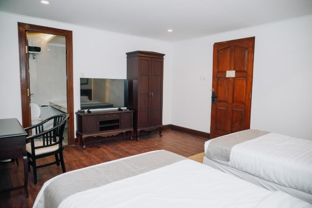 A hotel room with a bed, a desk, a chair, a wardrobe, and a mirror.