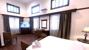 Una habitación de hotel con una cama, dos sillones, un escritorio, un televisor y una ventana.