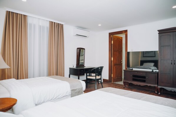 A hotel room with two beds, a desk with a chair, a wardrobe, and a door leading to another room. - HOTEL BUTIK SAWUNGGALING (Bandung)