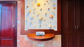 Een badkamer met een houten wastafelmeubel, een handdoek op het aanrecht en een muur versierd met schelpen.