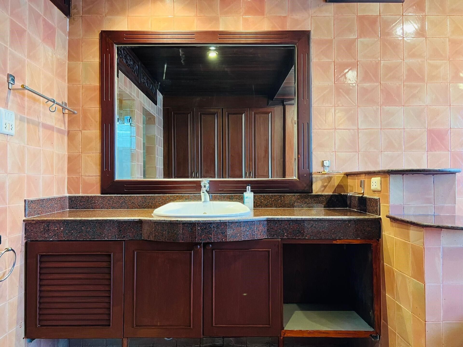 A bathroom with a large mirror, a sink, and wooden cabinets.