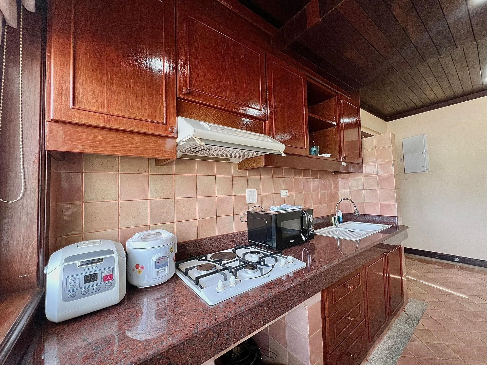A kitchen with wooden cabinets, a gas stove, a microwave, and a sink.