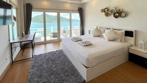 Een slaapkamer met een groot bed, een bureau en uitzicht op zee.