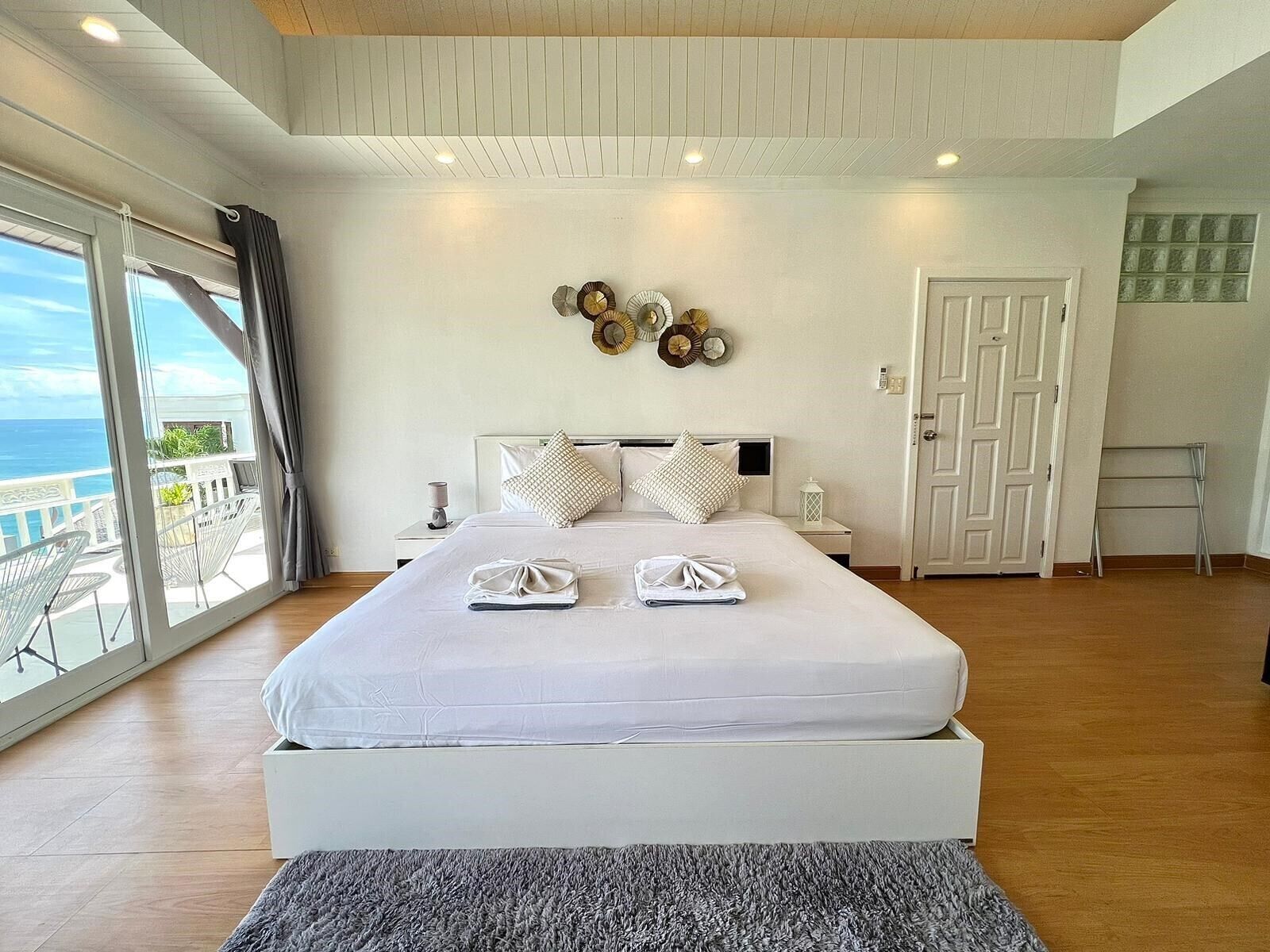 A spacious bedroom with a large bed, a balcony with a view, and a modern design.