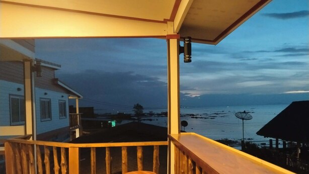 A wooden balcony with a view of the sea and a distant shoreline.
