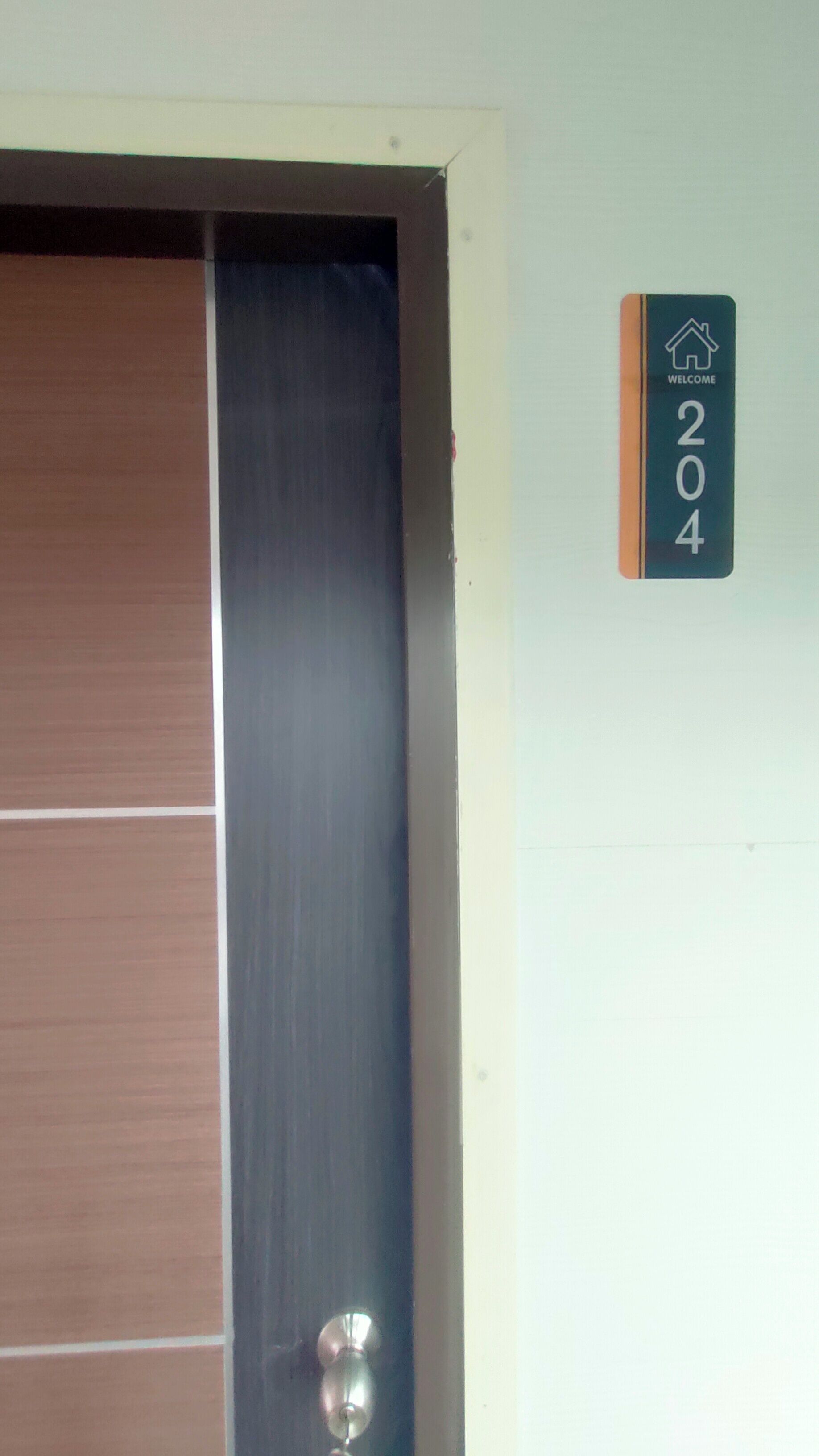 Une porte portant le numéro « 204 » et une pancarte de bienvenue au-dessus.