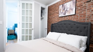 Un dormitorio con una cama grande, un muro de ladrillo y una puerta que da a otra habitación.