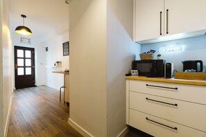 A compact kitchen with white cabinets, a microwave, a coffee machine, and a wooden countertop. - Townhouse Boutique  (Sibiu)