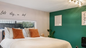 A bedroom with a bed, a window, a wall with a quote, and a green wall with a framed picture. - Pilgrim -  a holiday let that sleeps 2 guests  in 1 bedroom (Tenterden)