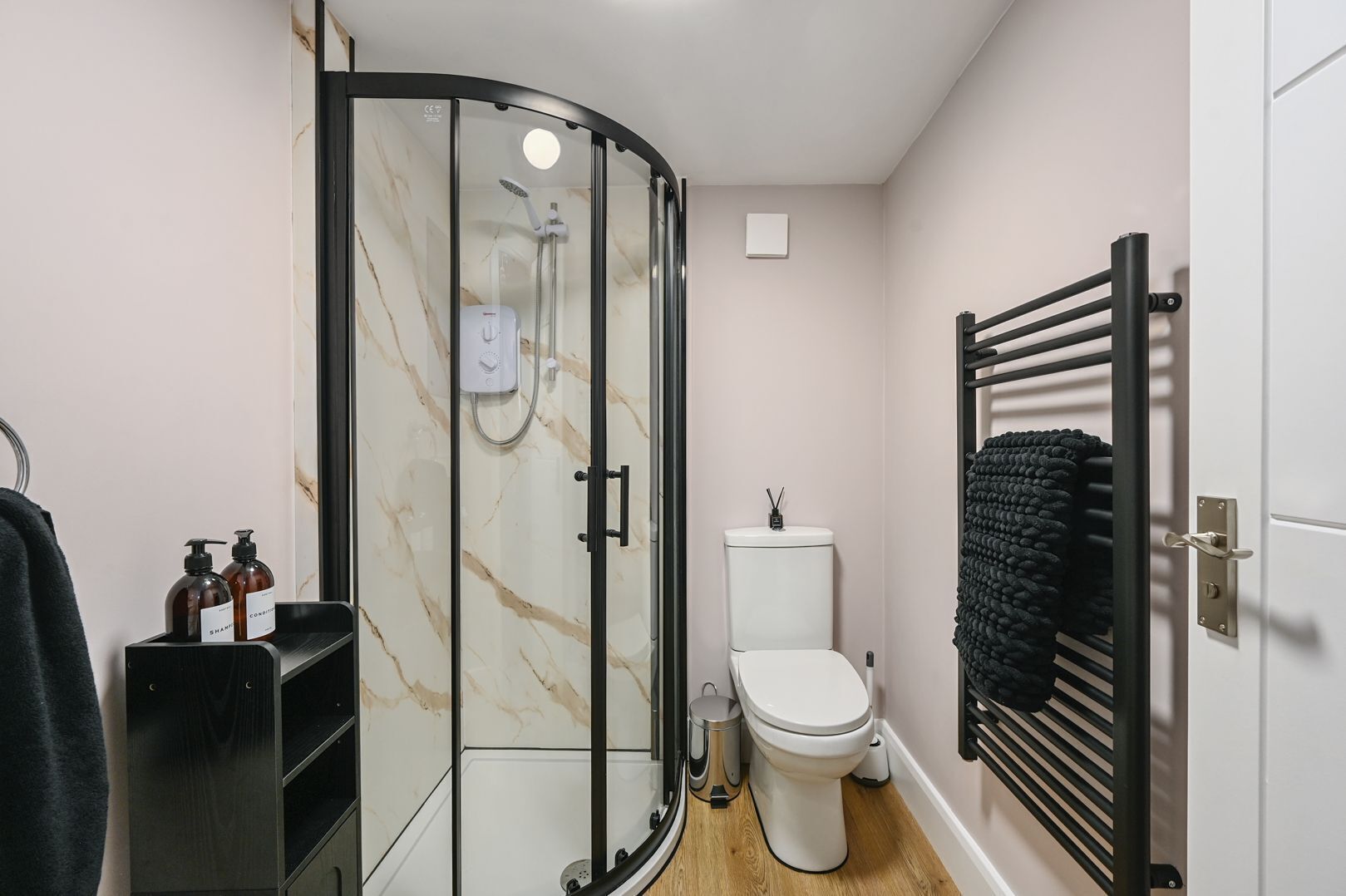 A modern bathroom with a glass-enclosed shower, a toilet, and a towel rack.