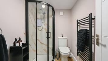 A modern bathroom with a glass-enclosed shower, a toilet, and a towel rack.