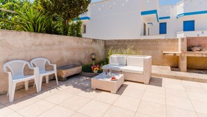 A patio area with white plastic chairs, a wicker sofa, and a small table with flowers. - Casa Fortuna By Vivimy (Taviano)