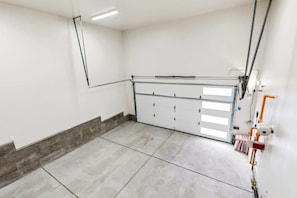 A clean, empty room with a large sliding door, a chain hoist, and a small table with a chair.