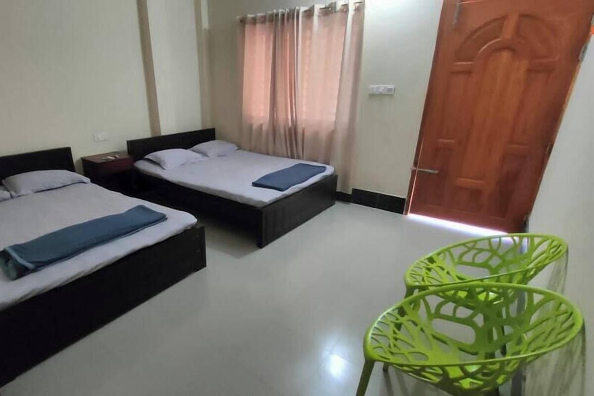 A room with two beds, a wooden door, and a green chair.