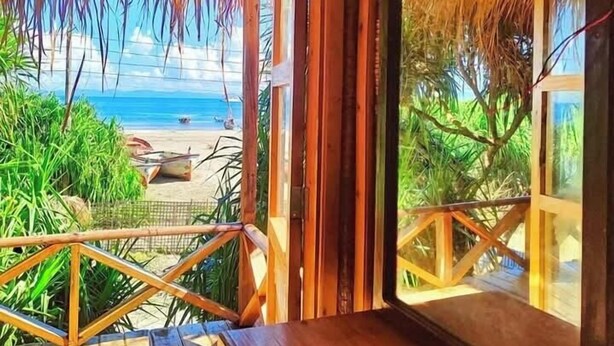 A wooden deck with a thatched roof overlooking a beach. - Sampan Beach Resort Saintmartin (Saint Martin's Island)