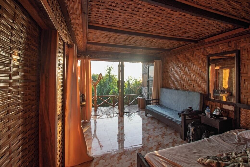Ein Zimmer mit Bett, einer Couch, einem Schreibtisch und einem Balkon mit Blick auf Grünflächen.