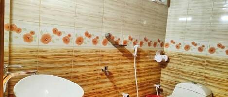A bathroom with a wooden vanity, a white sink, a toilet, and a shower area.