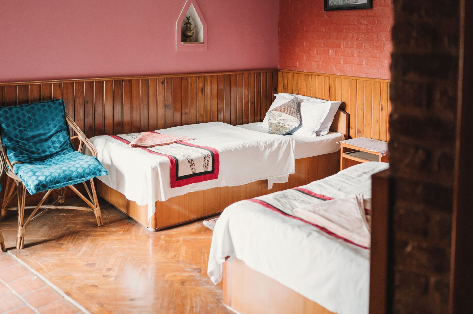 Una habitación con dos camas, una silla de madera y una mesita.