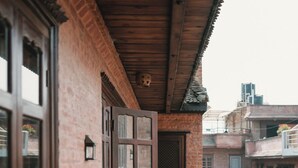 A balcony with a wrought iron railing, a wooden door, and a brick wall. - New Shiva Guest House (Bhaktapur)
