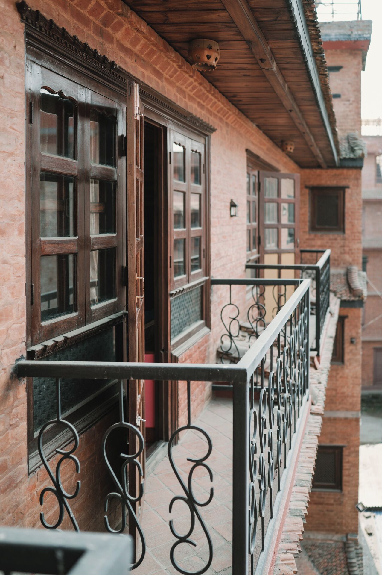 A brick building with large windows and a balcony with ornate metal railings.